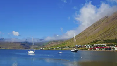 Segelboote liegen ruhig im Wasser vor einer malerischen Küstenstadt.