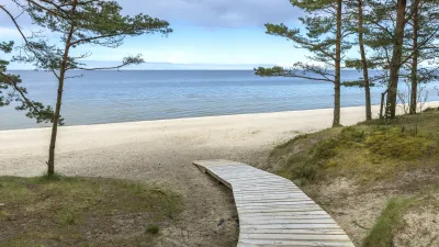 Holzsteg führt zum sandigen Strand mit Blick aufs Meer