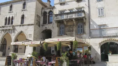 Café mit Tischen im Freien vor einem historischen Gebäude