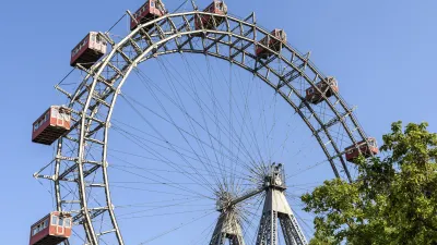 Das Wiener Riesenrad mit seinen roten Gondeln dreht sich am blauen Himmel.