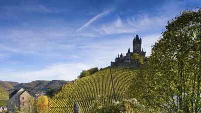 Burg Cochem thront auf einem grünen Hügel über Weinbergen