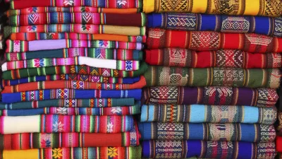 Bunte peruanische Stoffe sind gestapelt und bilden ein farbenfrohes Muster.