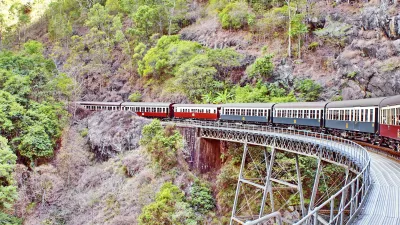 Roter Zug fährt über eine Eisenbahnbrücke in der australischen Landschaft