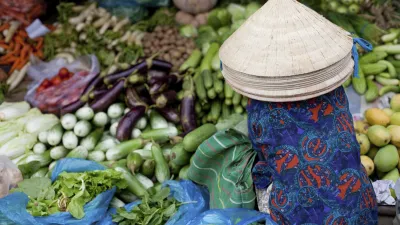 Frau mit traditionellem Hut verkauft frisches Gemüse auf dem Markt