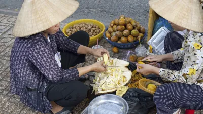 Zwei Frauen bereiten auf der Straße Obst zu und verkaufen es.