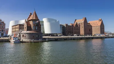 Das moderne Ozeaneum in Stralsund mit historischen Gebäuden am Wasser.