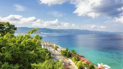 Karibische Küstenlandschaft mit türkisfarbenem Meer und Gebäuden.