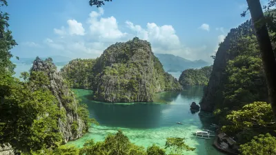Grüne Inseln ragen aus dem türkisfarbenen Wasser der Coron Bucht hervor.