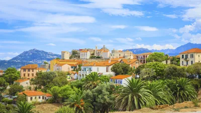 Korsische Stadt Calvi mit roten Dächern und grüner Vegetation.
