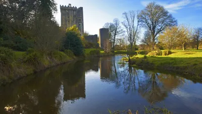 Blarney Castle spiegelt sich im Wasser eines ruhigen Flusses wider