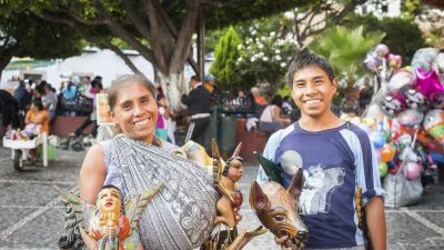 Zwei lächelnde Menschen präsentieren traditionelle mexikanische Puppen.