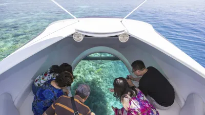 Touristen blicken durch Glasbodenboot auf Korallenriff