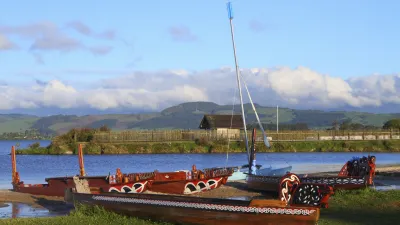 Traditionelle Maori-Kanus liegen am Ufer eines Sees.