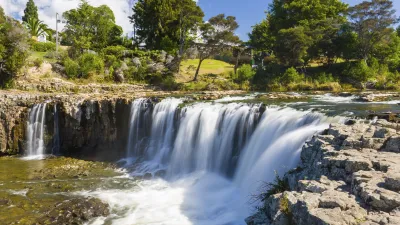 Ein breiter Wasserfall stürzt über Felsen in ein ruhiges Becken.
