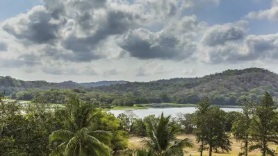 Panoramablick auf einen See, umgeben von üppiger Vegetation und Hügeln.