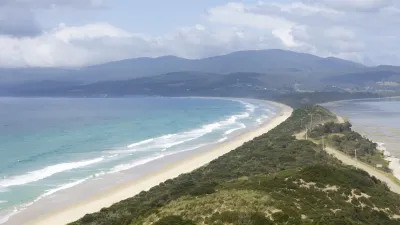 Türkisblaues Meer trifft auf einen goldenen Sandstrand mit grüner Vegetation.