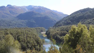 Patagonischer See zwischen grünen Hügeln und Bergen.