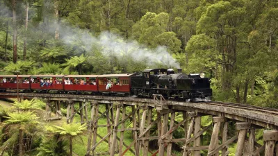 Historische Dampflok fährt über eine hölzerne Brücke im Wald