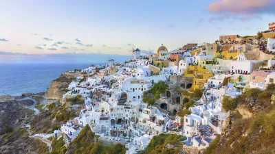 Weiß getünchte Häuser an der Küste von Santorin mit Blick auf das blaue Meer.
