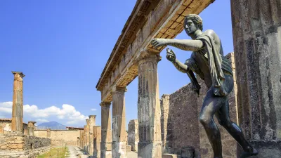 Antike Statue eines Mannes steht vor den Säulen eines Tempels in Pompeji