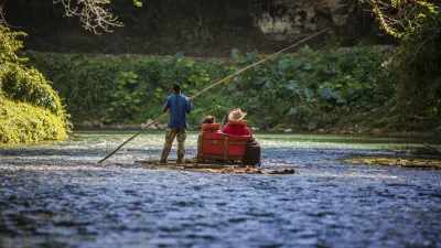 Ein Mann steuert ein Floß auf dem ruhigen Fluss Martha Brae.