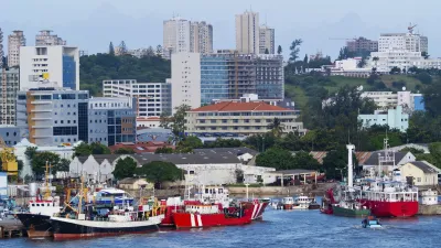 Bunte Fischerboote liegen im Hafen von Maputo vor der Skyline der Stadt.