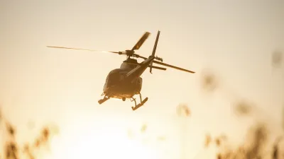 Ein Helikopter fliegt vor einem warmen Sonnenuntergang.
