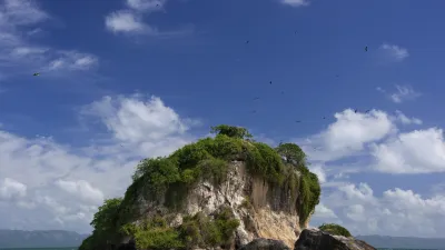 Grüne Felseninsel im türkisfarbenen Meer der Karibik.