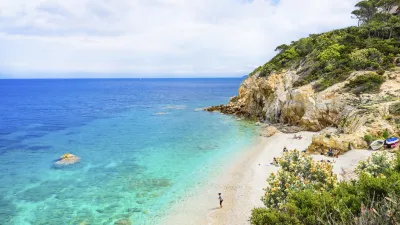 Türkisblaues Meer trifft auf einen sonnigen Sandstrand mit wenigen Badegästen.