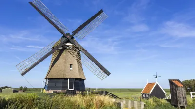 Historische Windmühle steht auf einem grünen Feld in den Niederlanden