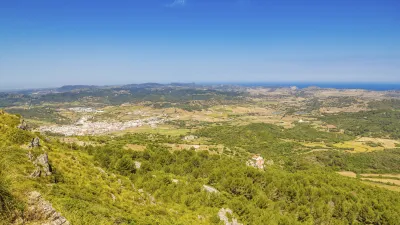 Panoramablick auf die grüne Landschaft und das Dorf von Menorca.