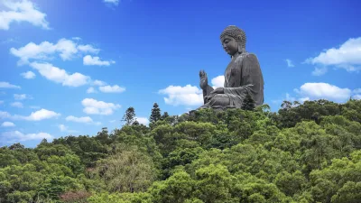 Große Buddha-Statue thront auf einem grünen Hügel in Hongkong.