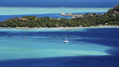 Türkisblaues Wasser umgibt eine tropische Insel mit üppiger Vegetation.