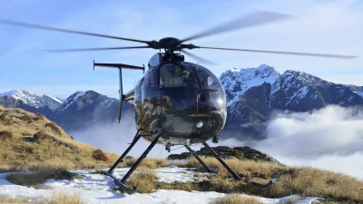 Helikopter steht auf einer Bergspitze mit Blick auf verschneite Gipfel