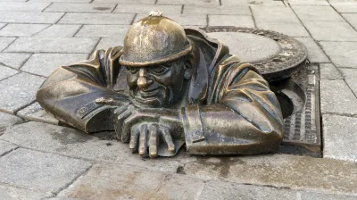 Ein Mann lugt aus einem Kanalisationsschacht heraus