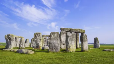 Historische Steinsäulen von Stonehenge stehen auf einer grünen Wiese.