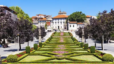 Gepflegter Garten mit geometrischen Hecken und einem historischen Gebäude im Hintergrund