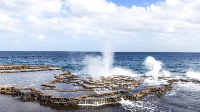 Spritzendes Wasser an felsiger Küste im tiefblauen Meer.