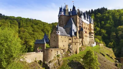 Burg Eltz thront majestätisch auf einem grünen Hügel.