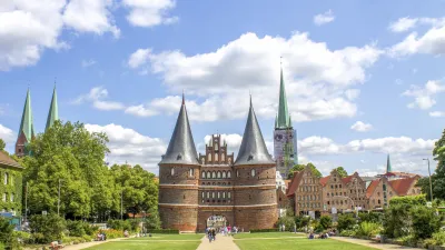Das historische Holstentor in Lübeck mit Grünflächen im Vordergrund.