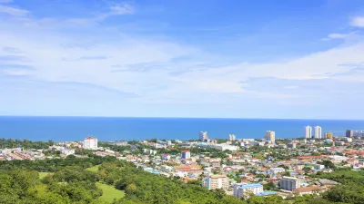 Blick über eine grüne Landschaft auf eine Stadt am Meer