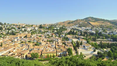 Historische Stadtansicht mit weißen Häusern und üppiger Vegetation.