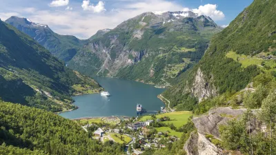 Norwegischer Fjord mit grüner Landschaft und kleinen Häusern.