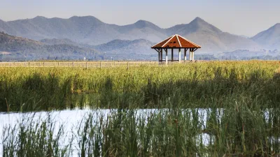 Ein Pavillon steht inmitten eines Sees mit Bergkulisse.