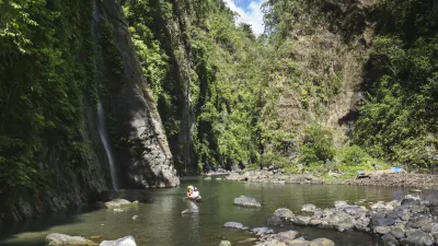 Kanu fährt auf einem Fluss unter steilen Felswänden.