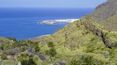 Straßenkurve führt zu Küstenortschaft mit Blick aufs Meer