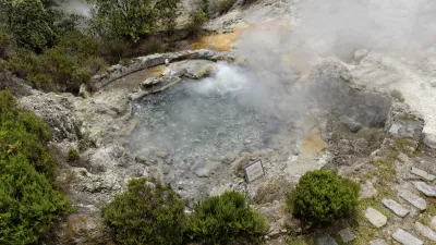 Dampfende heiße Quelle inmitten grüner Vegetation.
