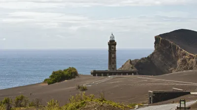 Leuchtturm Capelinhos steht auf vulkanischer Landschaft mit Blick aufs Meer.