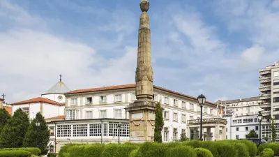 Historischer Obelisk vor einem weißen Gebäude mit spanischer Flagge