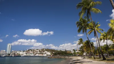 Karibischer Strand mit Palmen und Stadtbild im Hintergrund